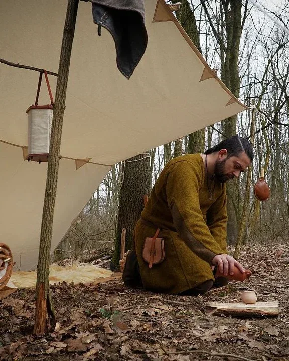 Camper working beneath a natural canvas tarp shelter