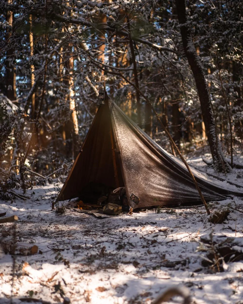 Abri en toile cirée brune dans un camp forestier enneigé