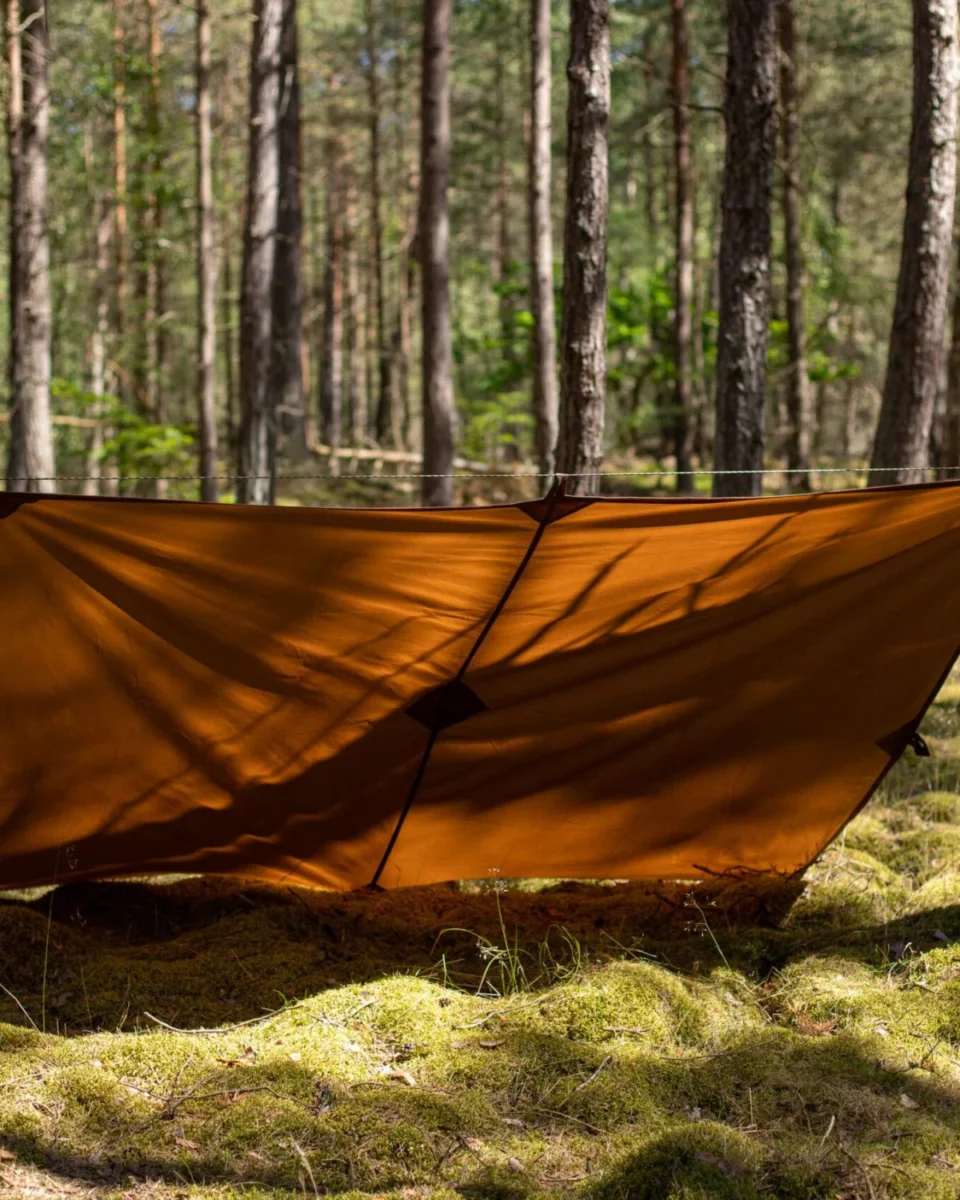 Bâche en toile cirée Nessmuk montée en abri bas entre les arbres