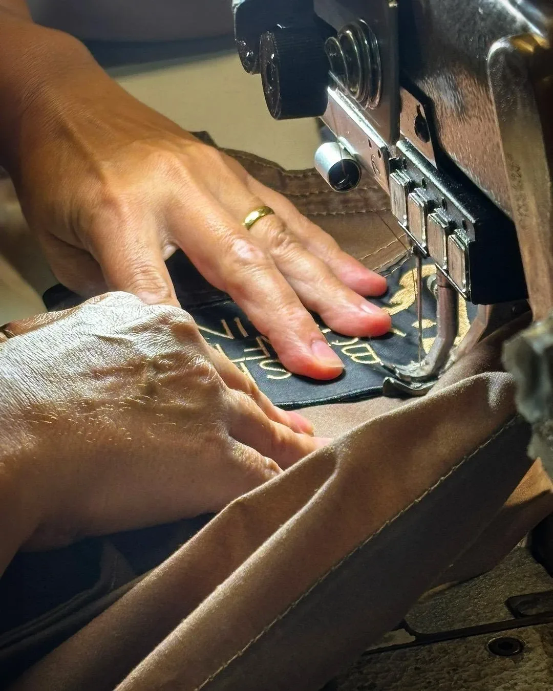 Hands guiding oilskin fabric at the sewing machine