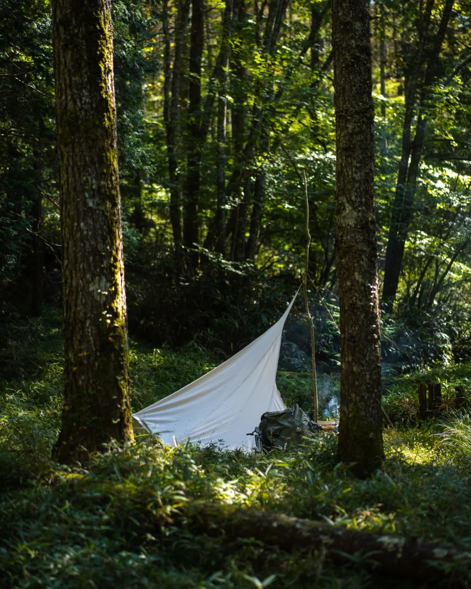 Finnischer Loue-Unterstand aus naturfarbenem Canvas auf einer grünen Waldlichtung