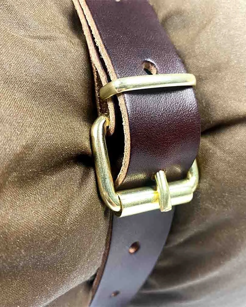 Nahaufnahme des Lederträgerriemens und der messingfarbenen Schnalle um ein Oilskin-Bedroll