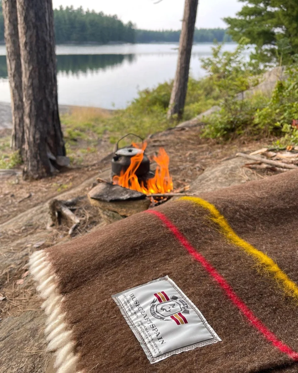 Braune Merinowolldecke neben einem Lagerfeuer mit Blick auf einen See