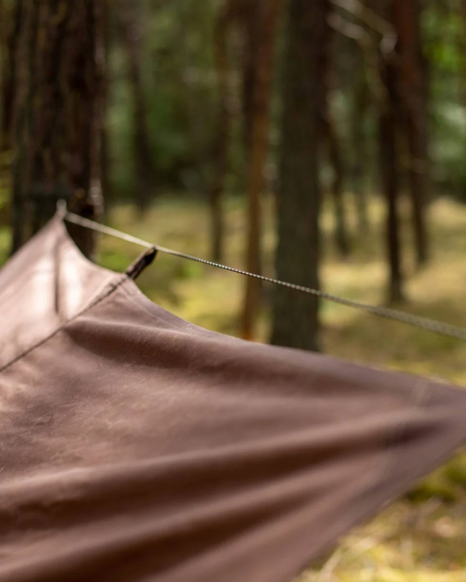 Vue rapprochée du faîtage d’une bâche en toile cirée et de sa cordelette tendue