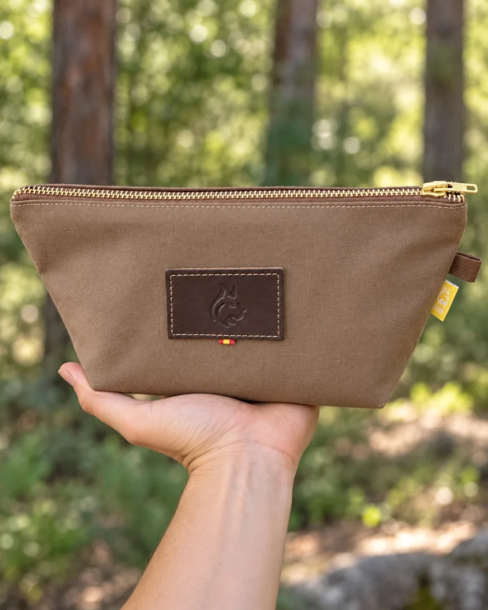 Brown oilskin travel bag with new fabric, brass zip and leather Bushcraft Spain logo, held in one hand