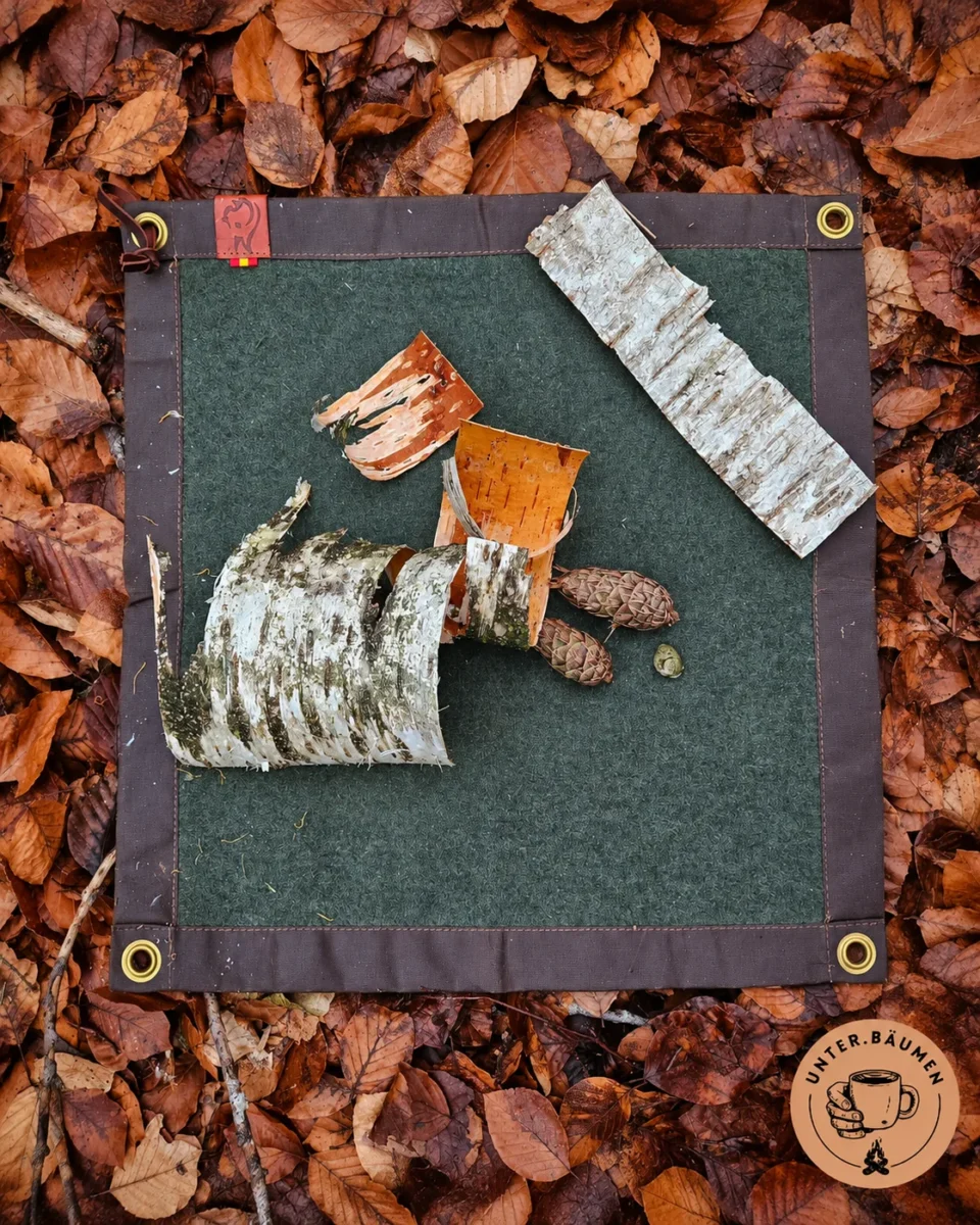 Green wool and oilskin mat with birch bark on autumn leaves