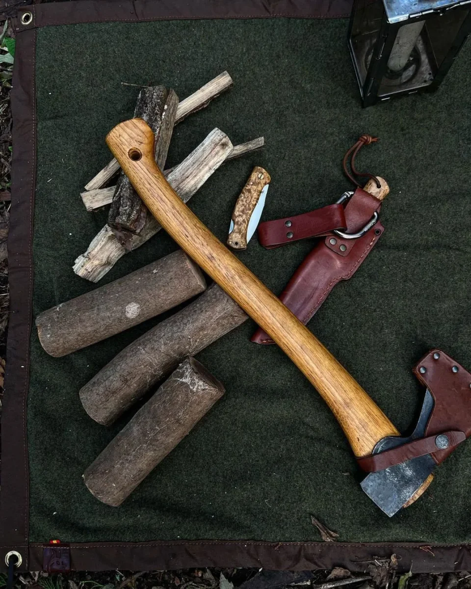 Axe, firewood and camp tools on a green wool and oilskin mat