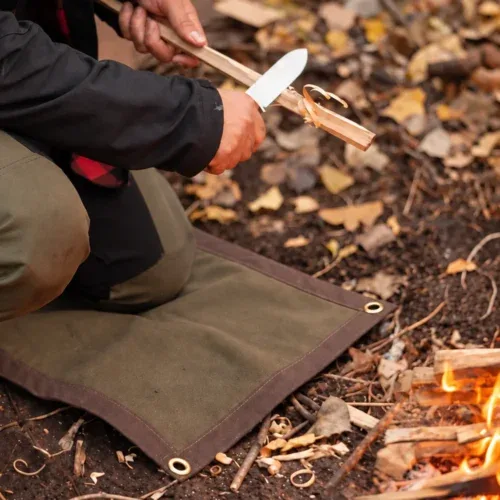 Oilskin mat used for kneeling while carving wood beside a campfire