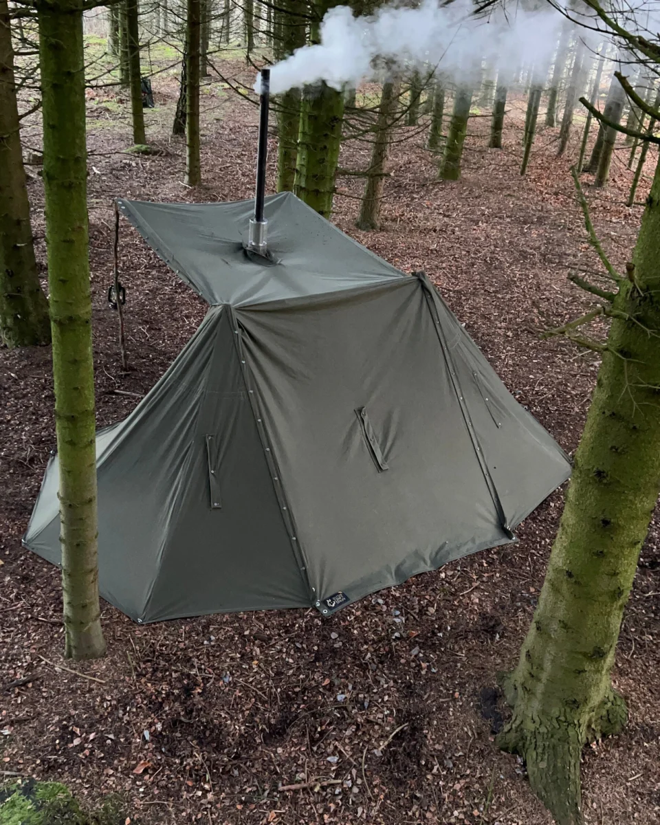 Lavvu de ponchos polacos con extensión y chimenea de estufa en el bosque
