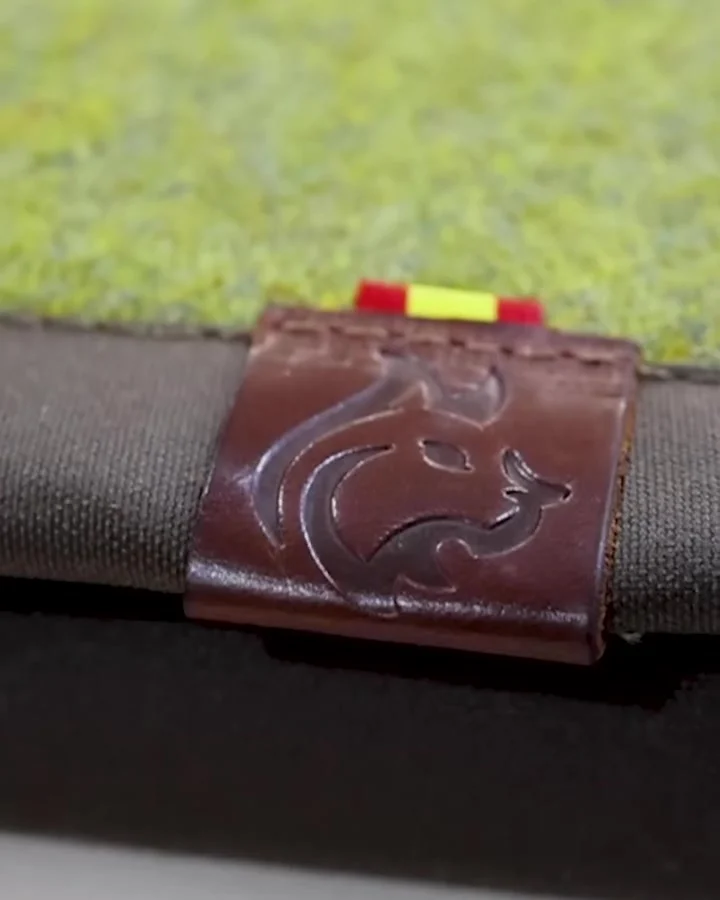 Etiqueta de cuero Bushcraft Spain sobre una esterilla estampada de lana Shetland