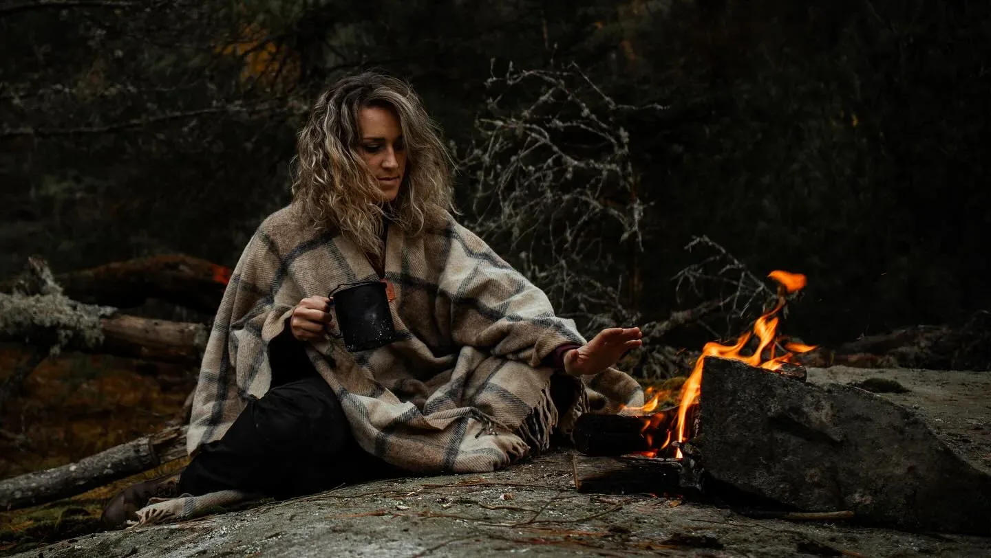 Wrapped in a wool blanket beside a woodland campfire